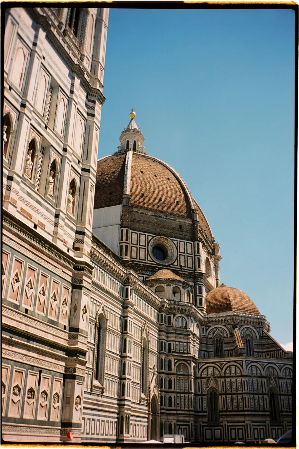 Florence Cathedral’s marble facade and dome against a blue sky in Florence, Tuscany, Italy, photographed on film by Khara from House of Lucie for an Elopement Collective elopement.