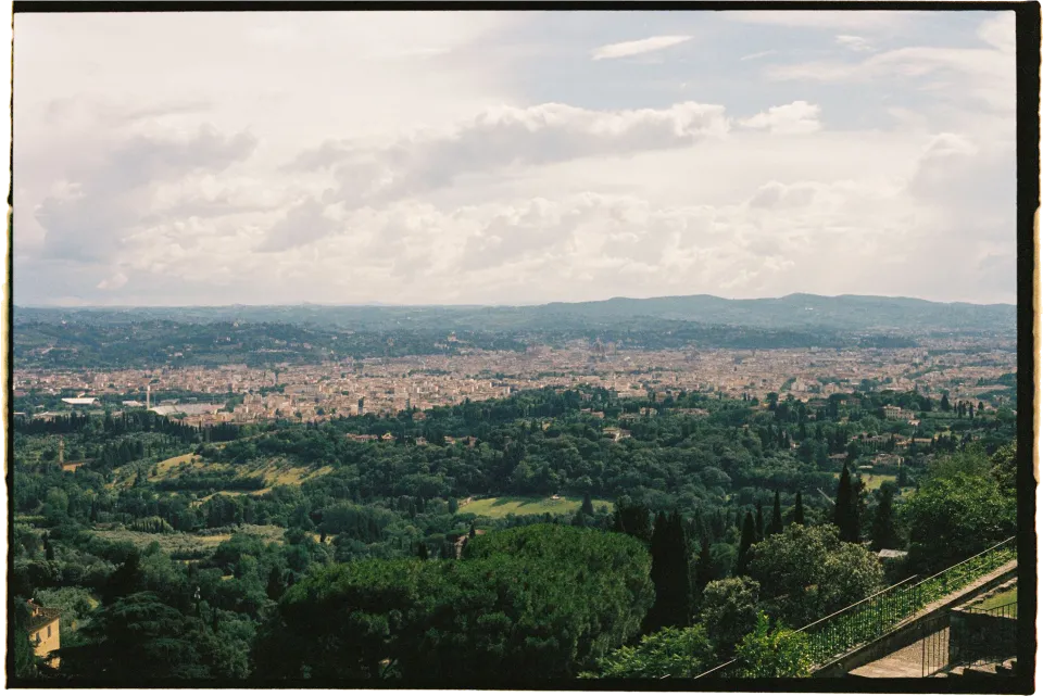 A wide view across Florence and green hills from the villa terrace, at Villa San Michele in Fiesole above Florence, Tuscany, Italy, for an Elopement Collective elopement. Film photograph by Khara from House of Lucie.