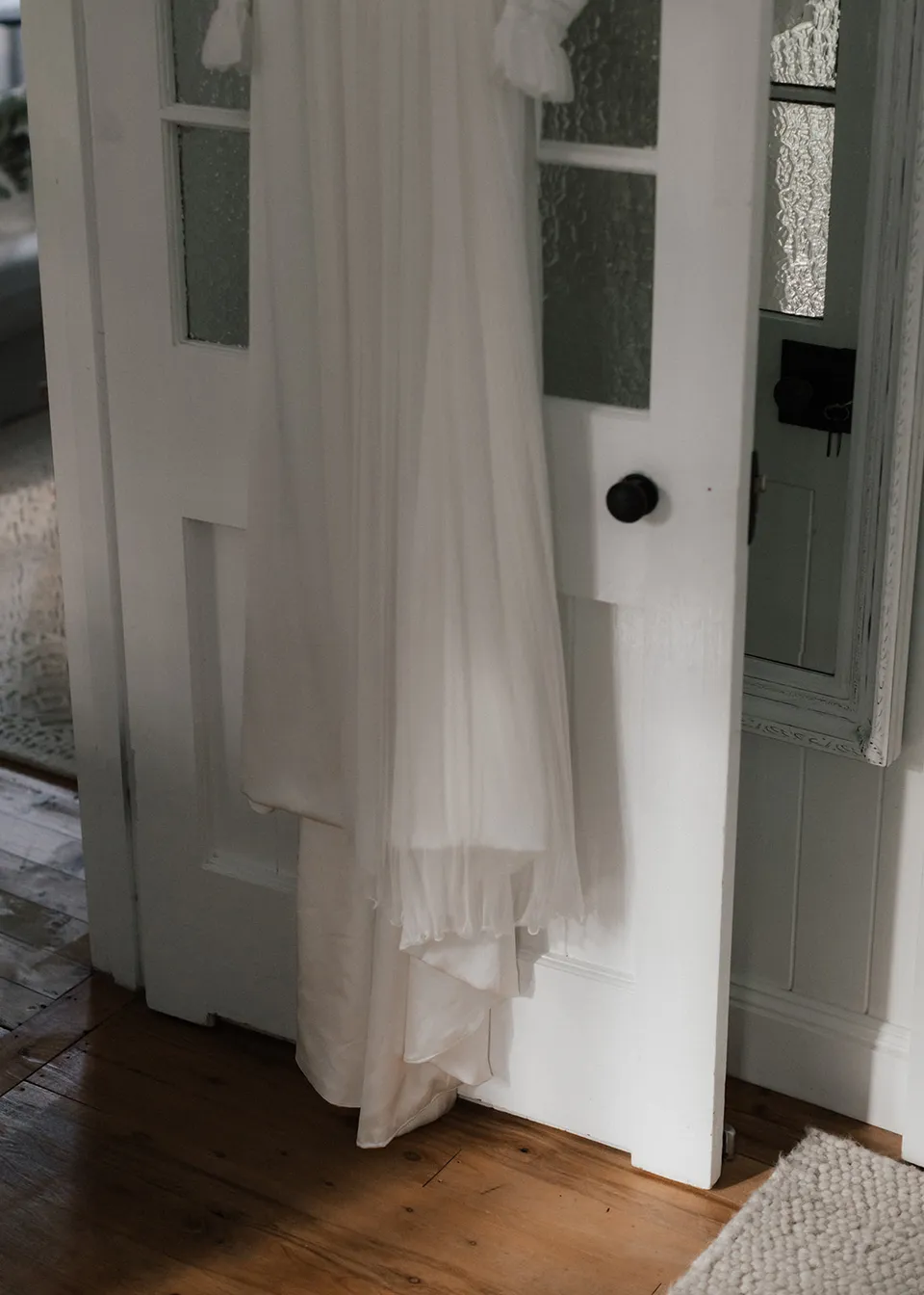 The hem of Elyse's wedding dress hanging above the timber floor. At Fig Tree Villa in Ewingsdale, Byron Bay, for an Elopement Collective elopement. Photograph by Bulb Creative.