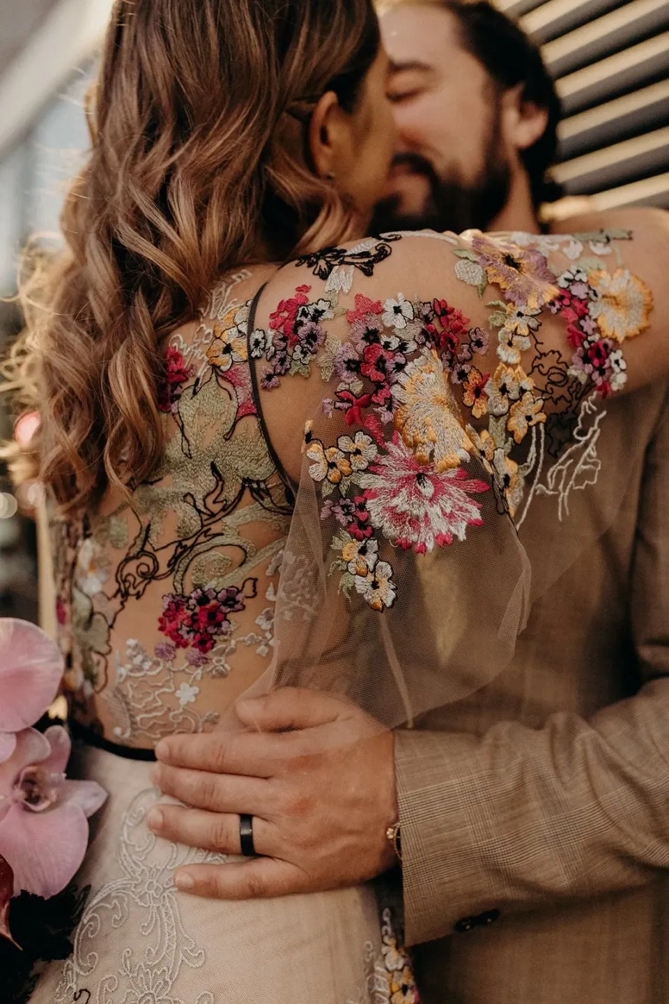 Close-up of Daniel’s hand and wedding ring on Victoria’s waist as they embrace in her floral dress, in Fortitude Valley, Brisbane, for an Elopement Collective elopement. Photo by Tessa Shannon.