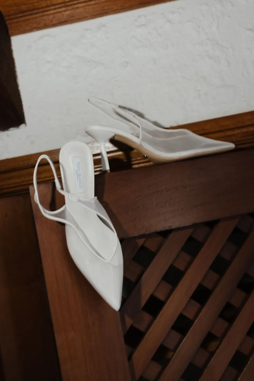 Renee’s white pointed slingback shoes arranged on a timber mantel against a white wall. At Piermont Retreat on Tasmania’s east coast, for an Elopement Collective elopement. Photograph by Bulb Creative.