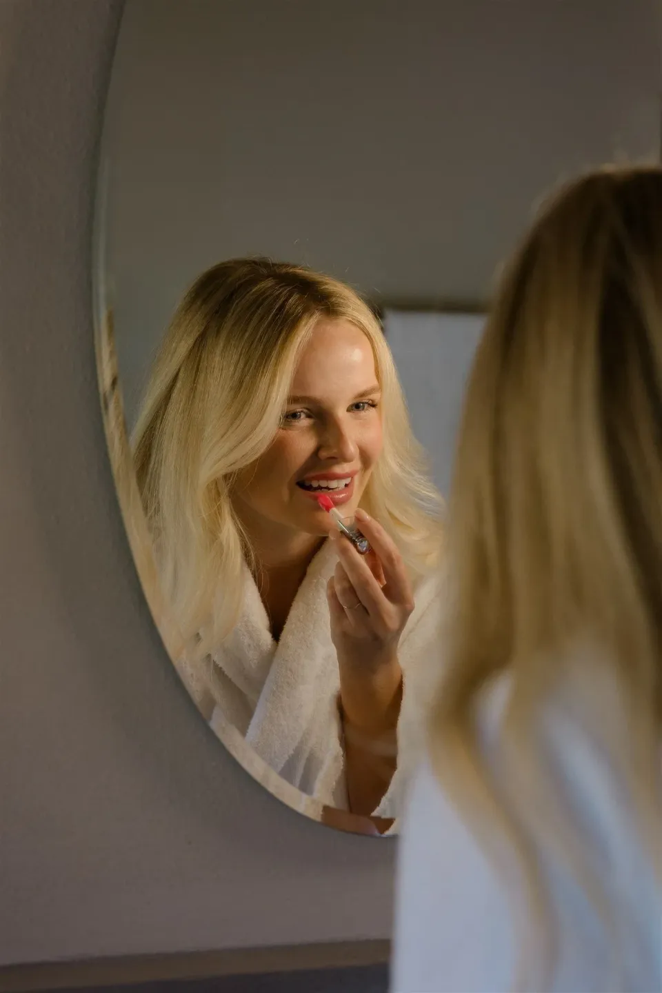 Shelby smiling at her reflection in a round mirror with a white tissue near her face, in Umbria, Italy, for an Elopement Collective elopement. Photo by James from House of Love.