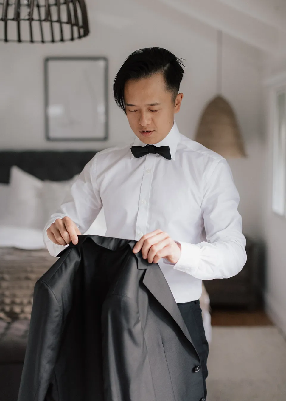 Jonathan holding his black suit jacket, ready to put it on. At Fig Tree Villa in Ewingsdale, Byron Bay, for an Elopement Collective elopement. Photograph by Bulb Creative.