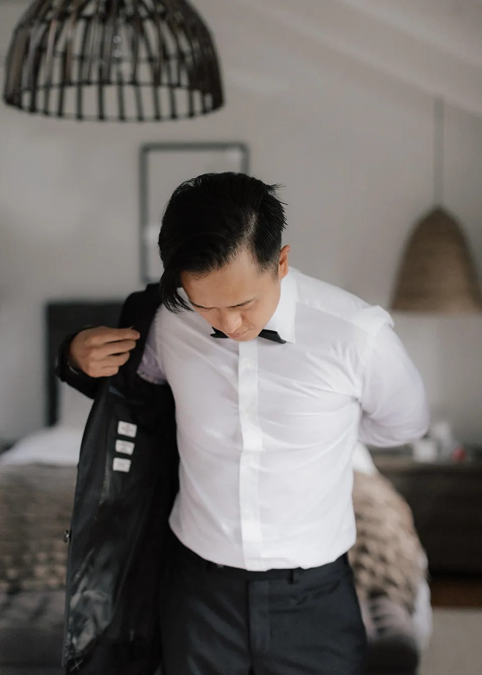 Jonathan slipping his arms into his suit jacket. At Fig Tree Villa in Ewingsdale, Byron Bay, for an Elopement Collective elopement. Photograph by Bulb Creative.