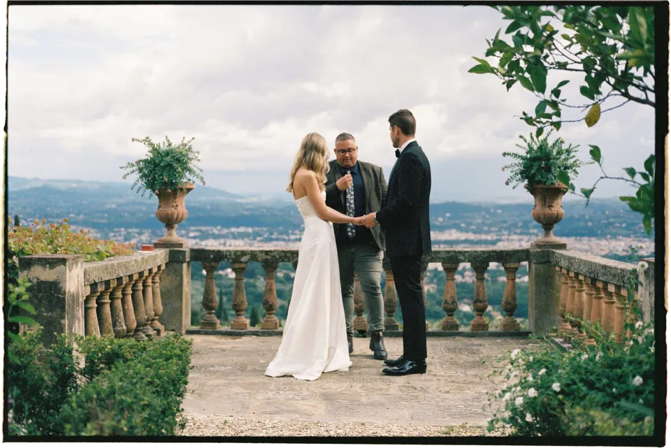 Josh Withers standing with Holly and Matthew during their intimate terrace ceremony above Florence, at Villa San Michele in Fiesole above Florence, Tuscany, Italy, for an Elopement Collective elopement. Film photograph by Khara from House of Lucie.