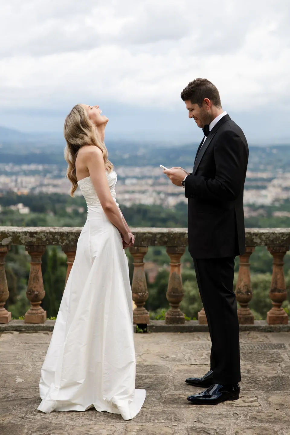 Matthew reading from his vow card while Holly listens, with Florence behind the terrace, at Villa San Michele in Fiesole above Florence, Tuscany, Italy, for an Elopement Collective elopement. Digital photograph by Khara from House of Lucie.