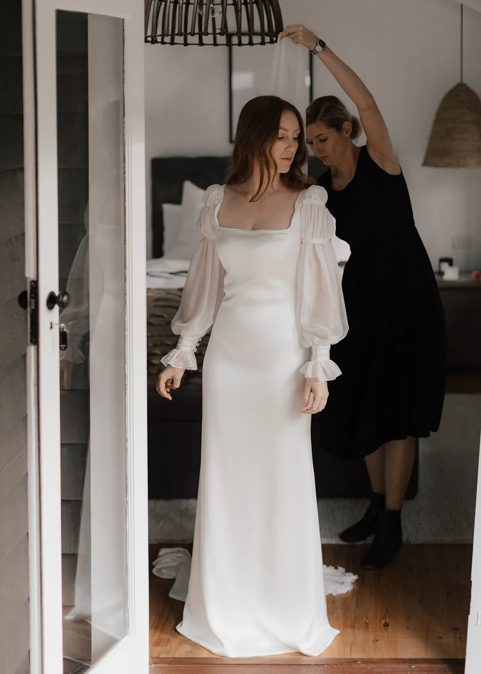 Elyse having her veil placed in her hair in the bedroom doorway. At Fig Tree Villa in Ewingsdale, Byron Bay, for an Elopement Collective elopement. Photograph by Bulb Creative.