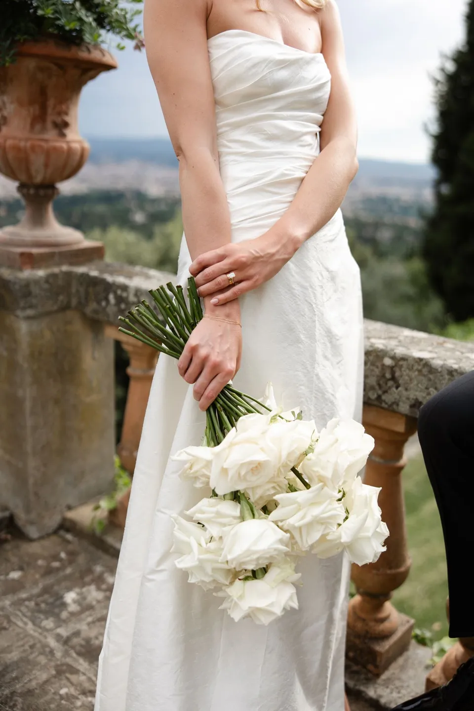 Close view of Holly’s white bouquet by Le Francesche Flower Designers against her draped wedding dress, at Villa San Michele in Fiesole above Florence, Tuscany, Italy, for an Elopement Collective elopement. Digital photograph by Khara from House of Lucie.