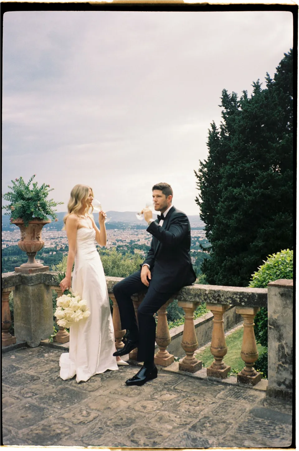 Holly and Matthew sharing a drink beside the stone balustrade above Florence, at Villa San Michele in Fiesole above Florence, Tuscany, Italy, for an Elopement Collective elopement. Film photograph by Khara from House of Lucie.