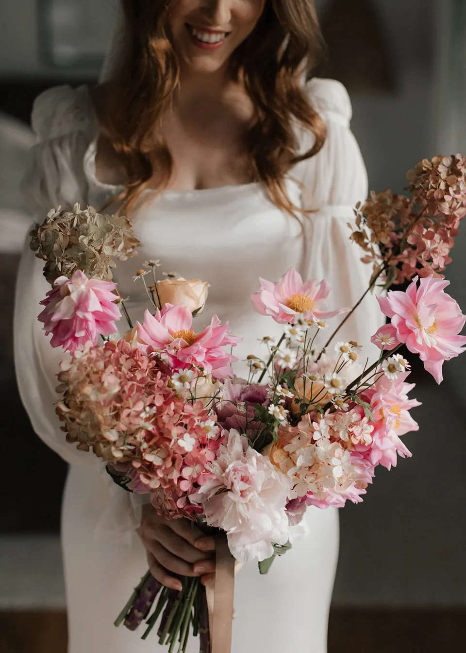 Elyse holding her colourful bouquet against her white dress, with flowers by The Perfect Party Co. At Fig Tree Villa in Ewingsdale, Byron Bay, for an Elopement Collective elopement. Photograph by Bulb Creative.
