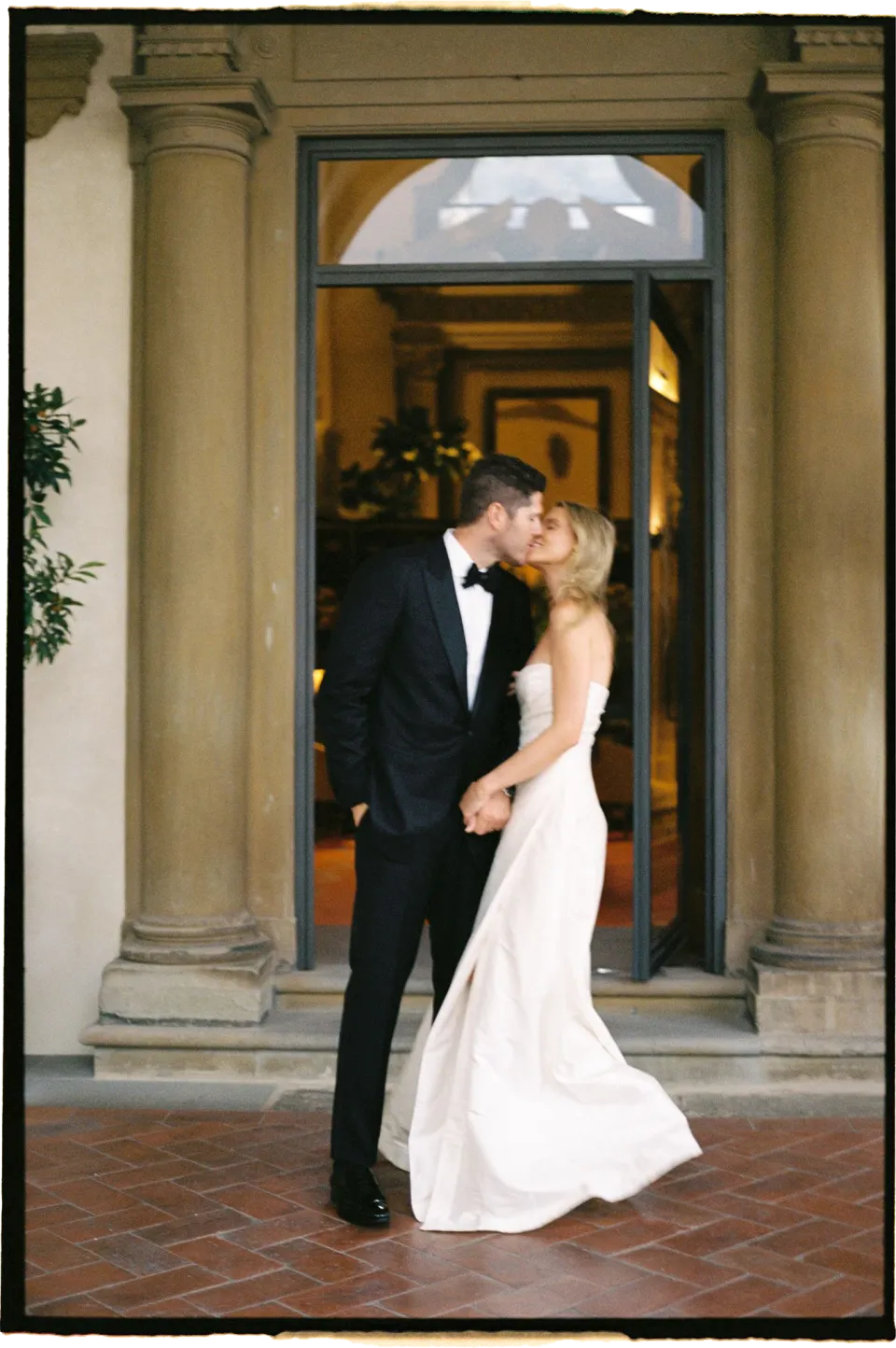 Holly and Matthew kissing in the villa’s stone doorway, at Villa San Michele in Fiesole above Florence, Tuscany, Italy, for an Elopement Collective elopement. Film photograph by Khara from House of Lucie.