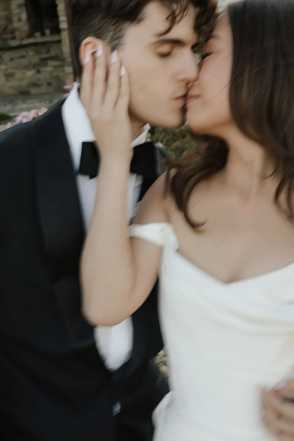 Close portrait of Clara and Harry kissing, with her hand against his cheek, at Thalia Haven on the East Coast of Tasmania, for an Elopement Collective elopement. Photograph by Bulb Creative.