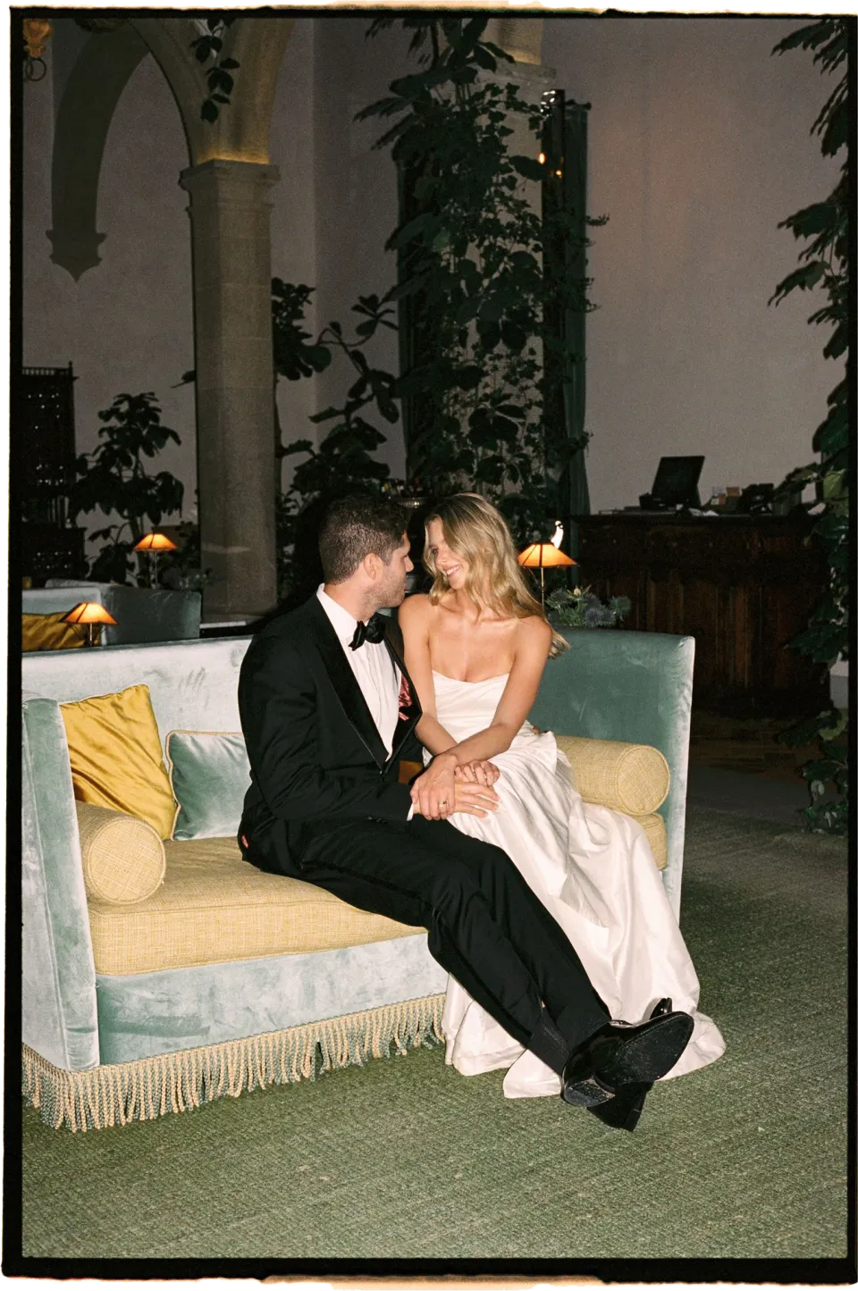Holly and Matthew holding each other close on a sofa beneath the villa’s arches, at Villa San Michele in Fiesole above Florence, Tuscany, Italy, for an Elopement Collective elopement. Film photograph by Khara from House of Lucie.