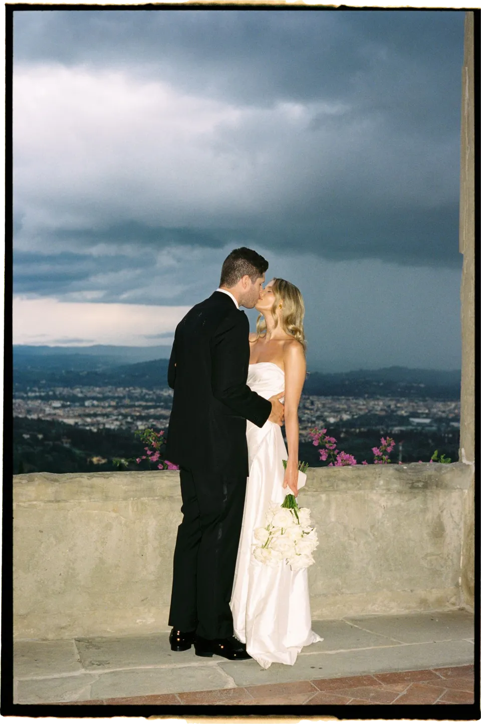 Holly and Matthew resting their foreheads together on the terrace overlooking Florence beneath dark clouds, at Villa San Michele in Fiesole above Florence, Tuscany, Italy, for an Elopement Collective elopement. Film photograph by Khara from House of Lucie.