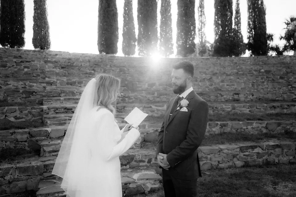 Black and white photograph of Kaitlyn reading her vows to Russell in the stone amphitheatre. At Piermont Retreat on Tasmania’s east coast, for an Elopement Collective elopement. Photograph by Omar of By The Wilde.