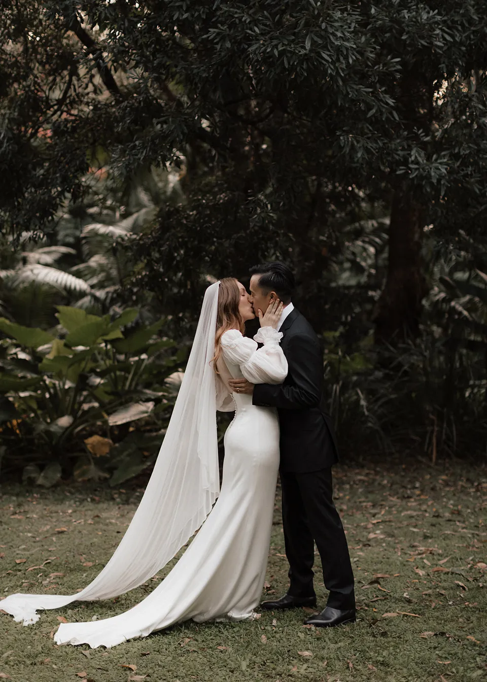 Elyse and Jonathan embracing on the lawn after their ceremony. At Fig Tree Villa in Ewingsdale, Byron Bay, for an Elopement Collective elopement. Photograph by Bulb Creative.