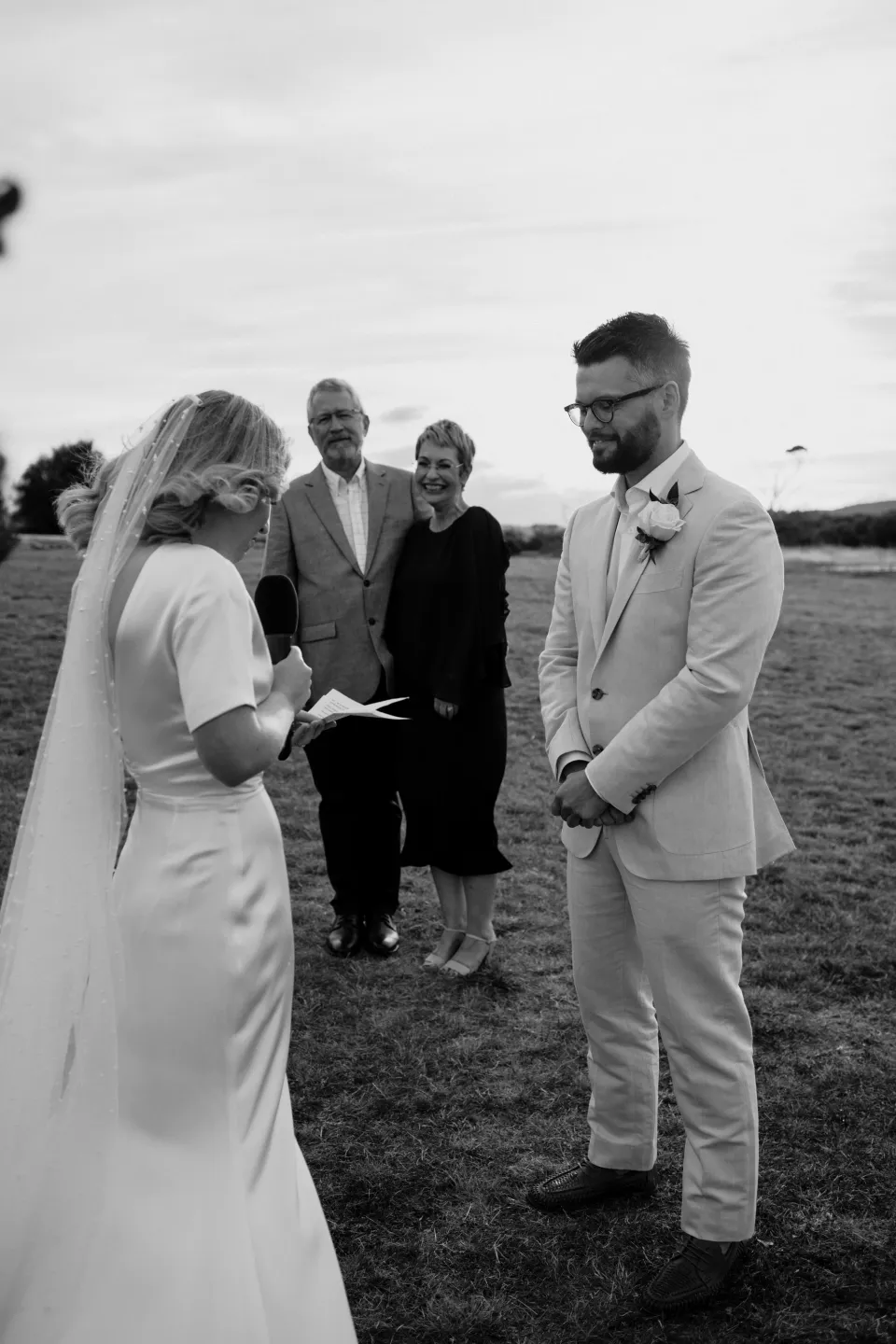 Black and white photograph of Jemmah reading her vows to Jack, at Thalia Haven on the East Coast of Tasmania, Australia, for an Elopement Collective elopement. Photograph by Joey Willis.