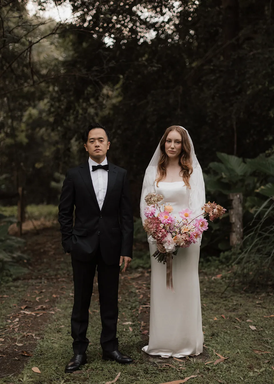 Elyse and Jonathan standing side by side for a garden portrait. At Fig Tree Villa in Ewingsdale, Byron Bay, for an Elopement Collective elopement. Photograph by Bulb Creative.