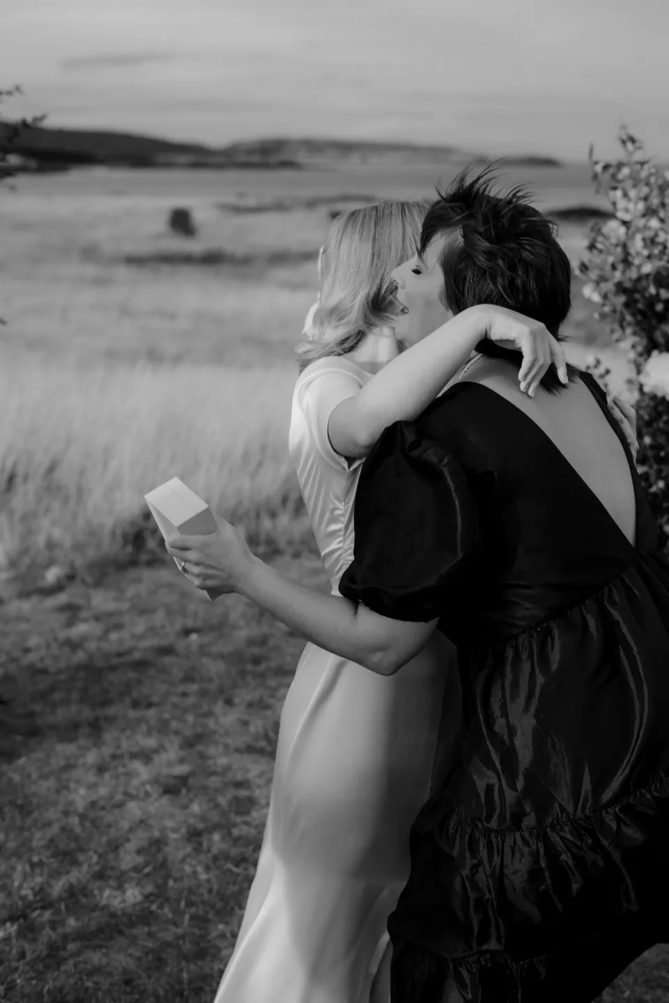Black and white photograph of Jemmah embracing a loved one after the ceremony, at Thalia Haven on the East Coast of Tasmania, Australia, for an Elopement Collective elopement. Photograph by Joey Willis.