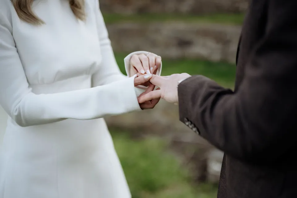 Close-up of Kaitlyn placing a wedding ring on Russell’s hand during their ceremony. At Piermont Retreat on Tasmania’s east coast, for an Elopement Collective elopement. Photograph by Omar of By The Wilde.
