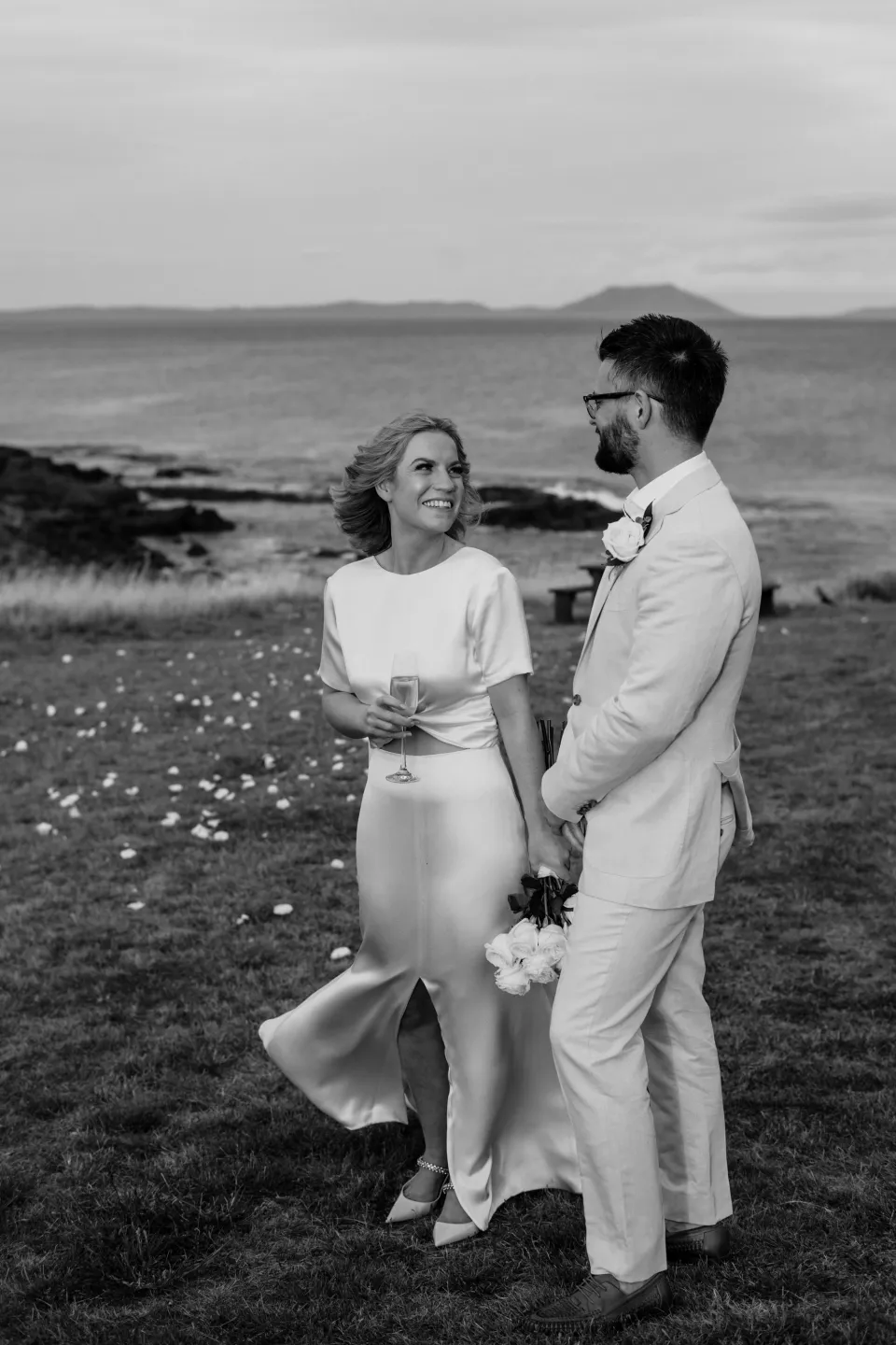 Black and white portrait of Jemmah and Jack smiling at each other, at Thalia Haven on the East Coast of Tasmania, Australia, for an Elopement Collective elopement. Photograph by Joey Willis.