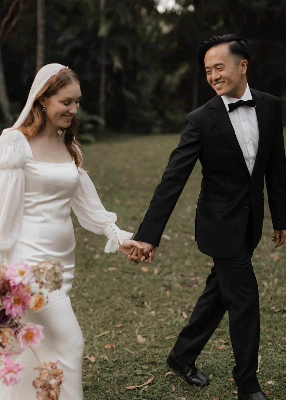 Jonathan smiling at Elyse as they walk across the lawn. At Fig Tree Villa in Ewingsdale, Byron Bay, for an Elopement Collective elopement. Photograph by Bulb Creative.