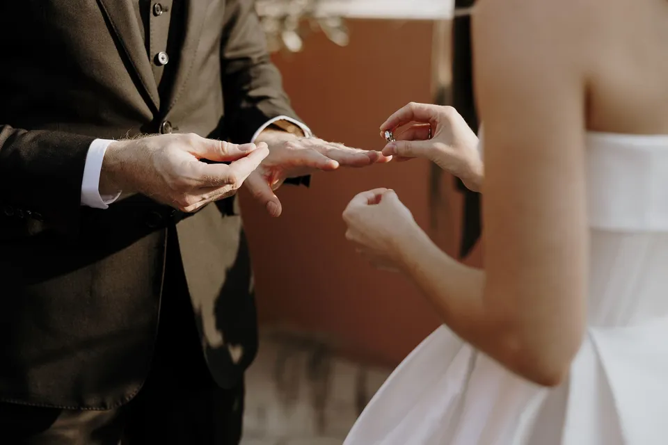 Close view of Danielle placing a wedding ring on Adam’s hand, at The Calile Hotel in Fortitude Valley, Brisbane, for an Elopement Collective elopement. Photo by George Bowden.