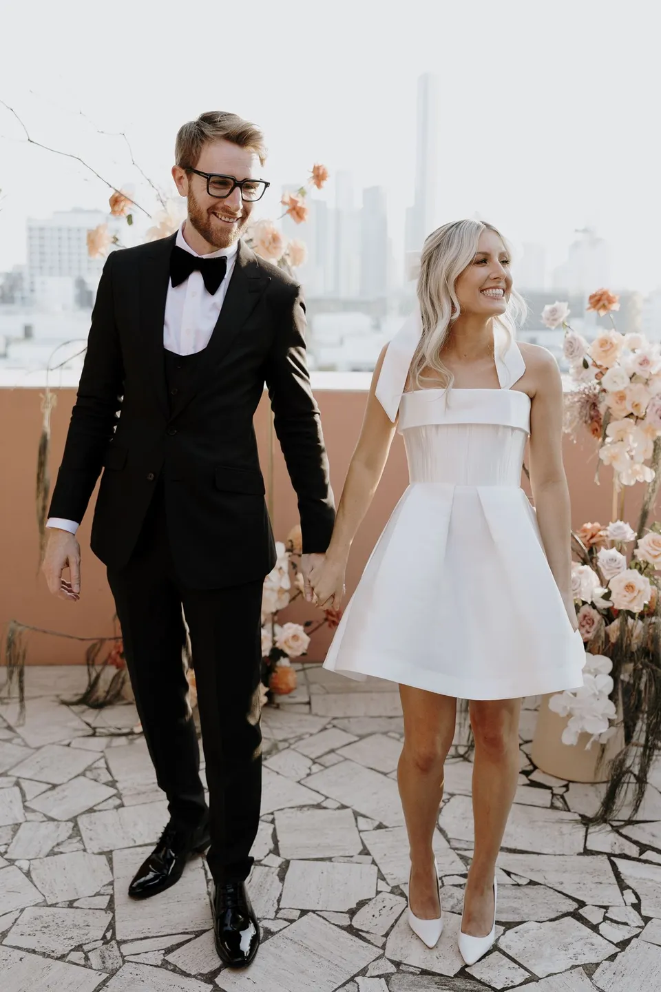 Danielle and Adam smiling and holding hands after their terrace ceremony, at The Calile Hotel in Fortitude Valley, Brisbane, for an Elopement Collective elopement. Photo by George Bowden.