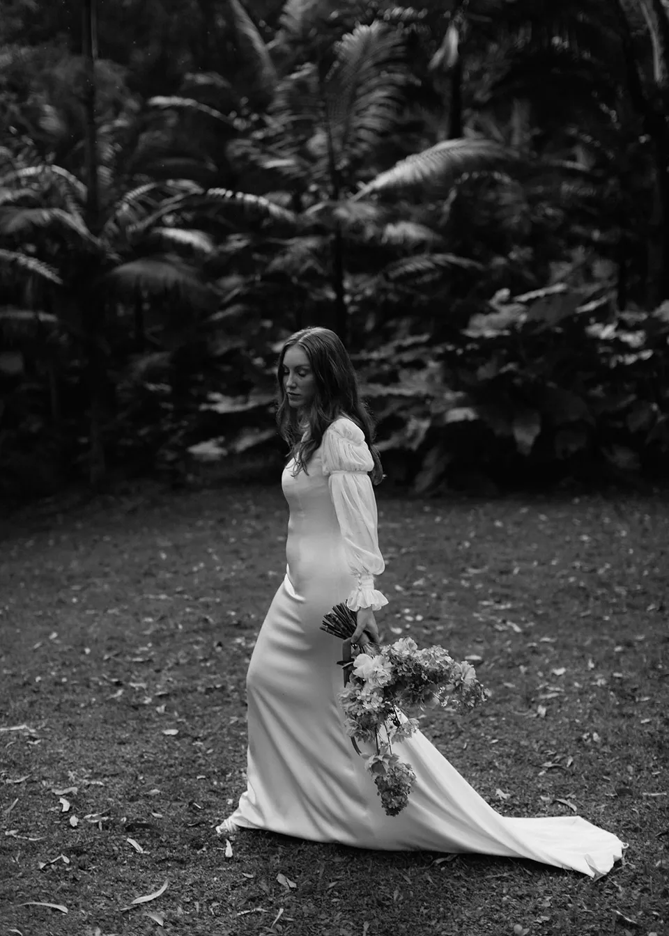 Black-and-white side portrait of Elyse with her bouquet and trailing dress, with flowers by The Perfect Party Co. At Fig Tree Villa in Ewingsdale, Byron Bay, for an Elopement Collective elopement. Photograph by Bulb Creative.
