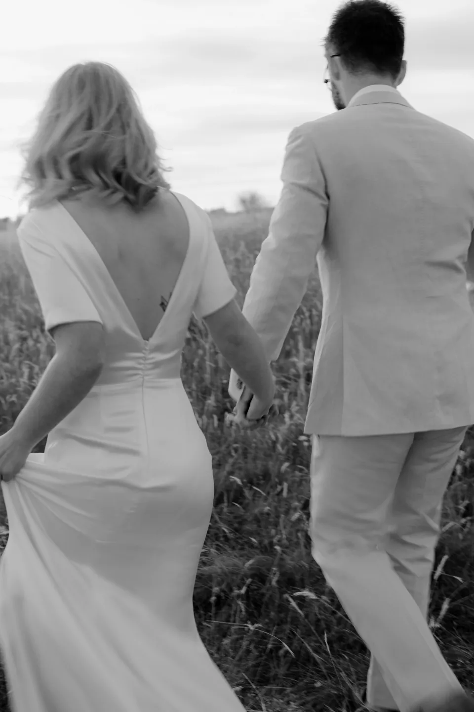 Black and white close view of the couple walking hand in hand, at Thalia Haven on the East Coast of Tasmania, Australia, for an Elopement Collective elopement. Photograph by Joey Willis.