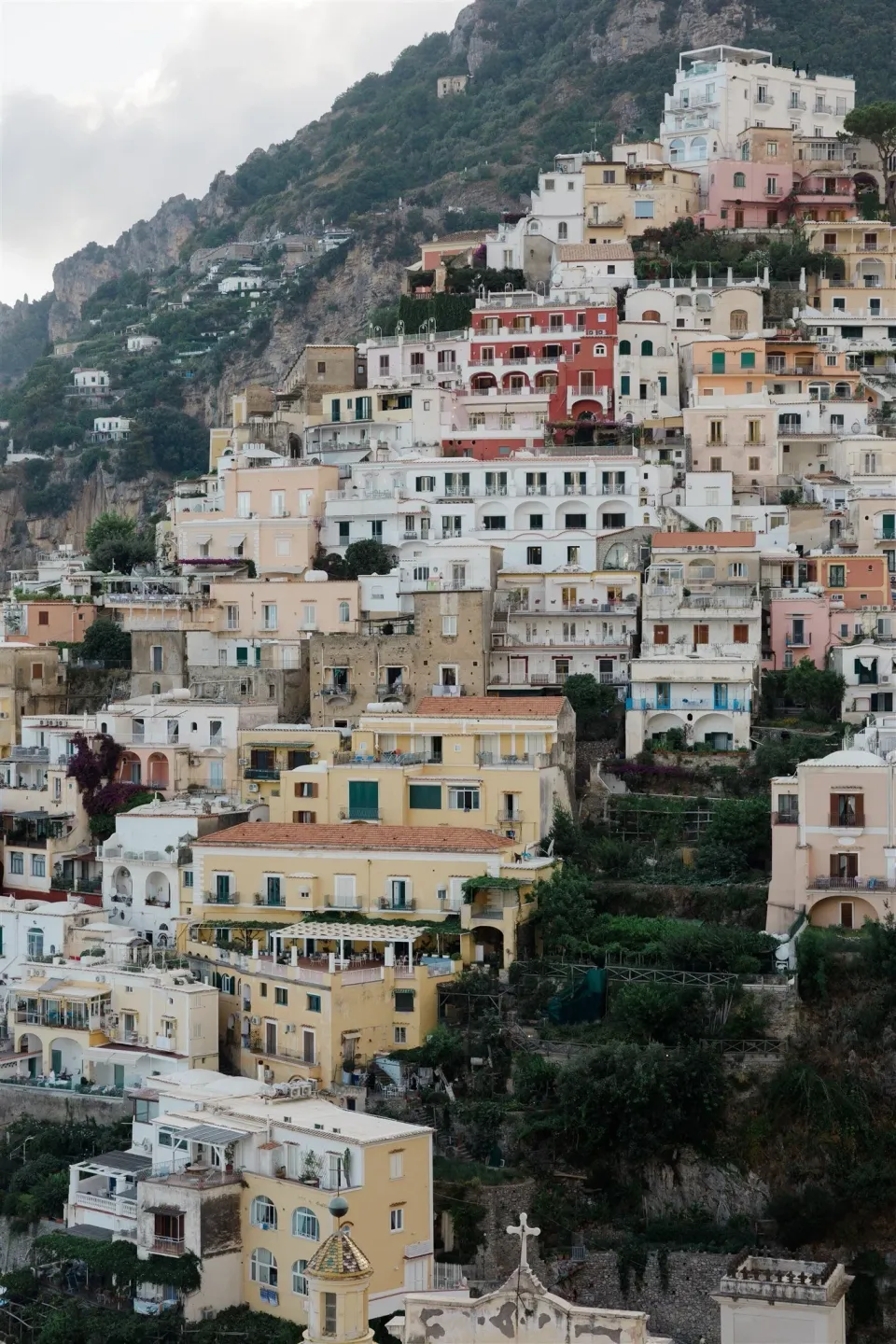 Pastel-coloured houses stacked across the steep hillside above the coastline, in Positano on Italy’s Amalfi Coast, for an Elopement Collective elopement. Photo by James from House of Love.