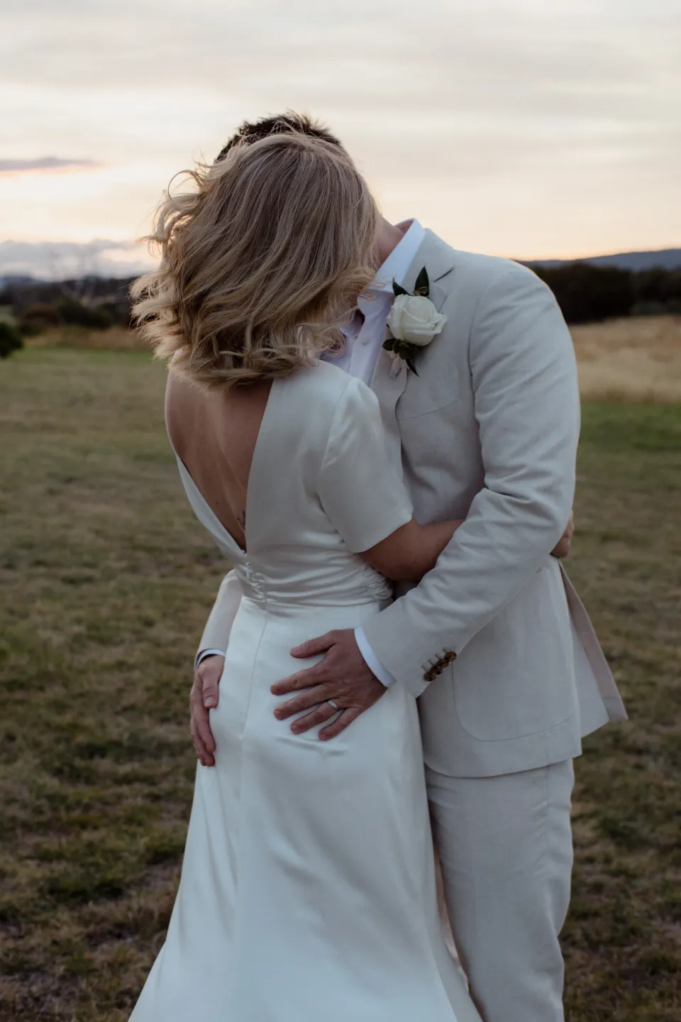 Jemmah and Jack embracing with her hair moving in the breeze, at Thalia Haven on the East Coast of Tasmania, Australia, for an Elopement Collective elopement. Photograph by Joey Willis.