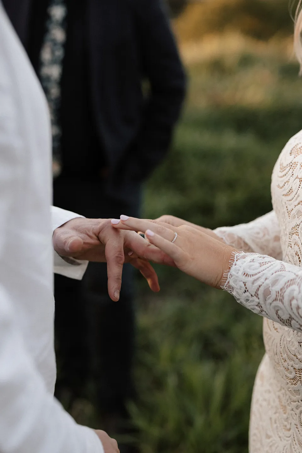 Laura sliding a wedding ring onto Matt’s finger during their outdoor ceremony, in the Tweed Valley, NSW, for an Elopement Collective elopement. Photo by Bulb Creative.