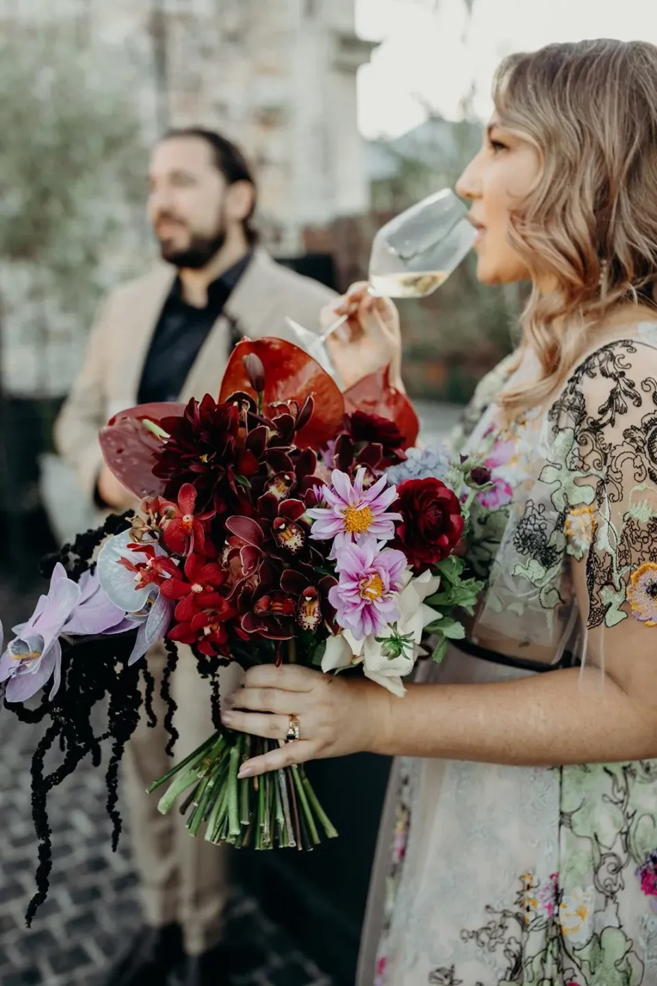 Victoria drinking sparkling wine beside Daniel while holding her bouquet by Mrs Gibbons Flowers, at Agnes Restaurant in Fortitude Valley, Brisbane, for an Elopement Collective elopement. Photo by Tessa Shannon.