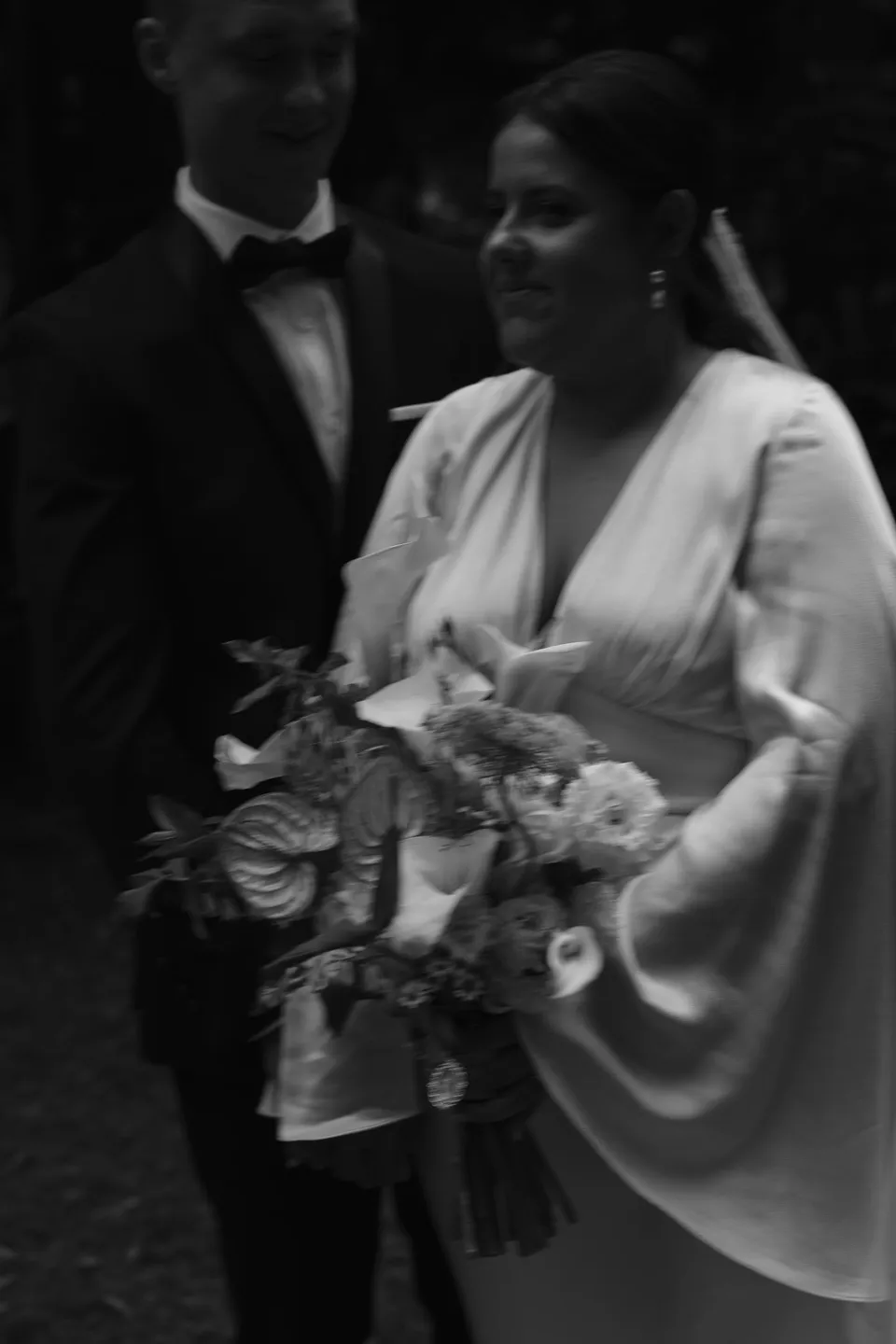 Black-and-white close portrait of Laura and Matthew with her bouquet. At Fig Tree Villa in Ewingsdale, Byron Bay, for an Elopement Collective elopement. Photograph by George Bowden.