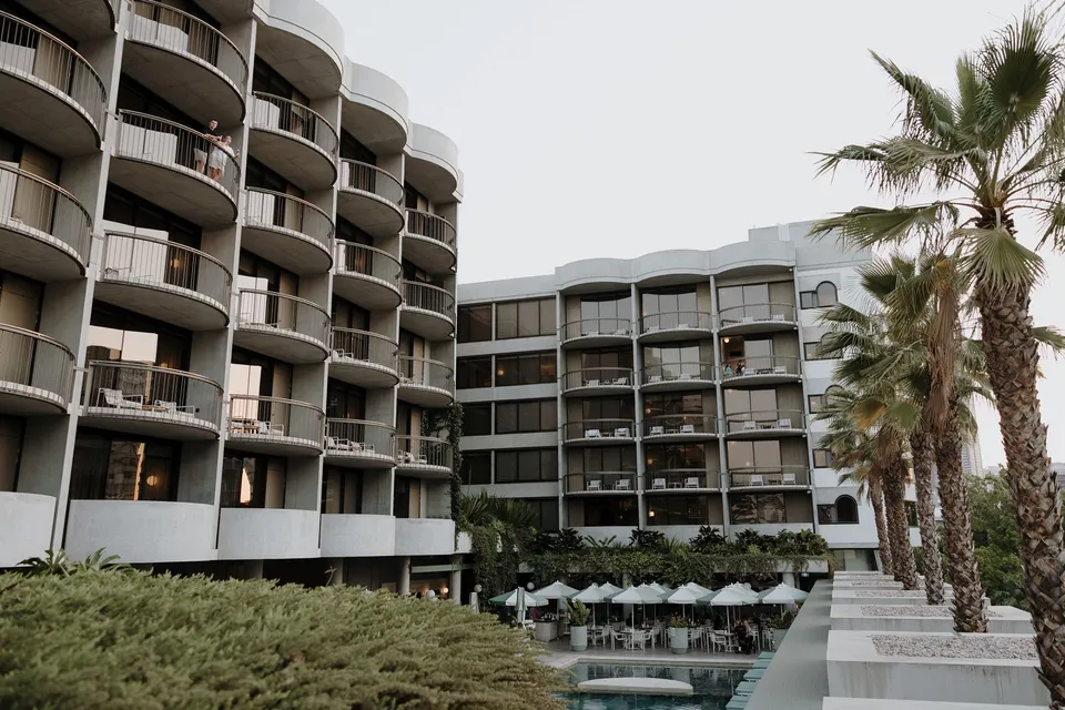 The hotel’s curved balconies, pool and palm trees, at The Calile Hotel in Fortitude Valley, Brisbane, for an Elopement Collective elopement. Photo by George Bowden.