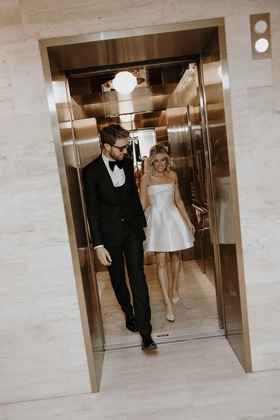 Danielle and Adam stepping out of the hotel’s gold mirrored lift, at The Calile Hotel in Fortitude Valley, Brisbane, for an Elopement Collective elopement. Photo by George Bowden.