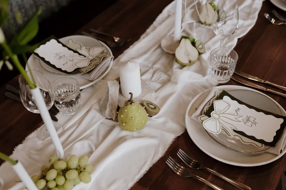 Place settings, glassware, white candles and green fruit on the reception table. At The Farm and Three Blue Ducks in Ewingsdale, Byron Bay, for an Elopement Collective elopement. Photograph by George Bowden.
