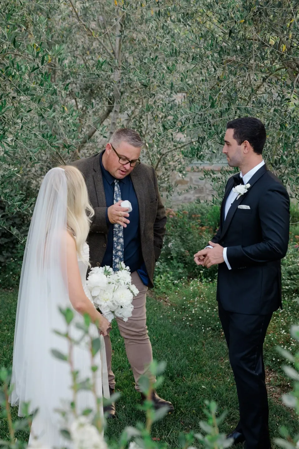 Shelby and Jack facing one another during their garden ceremony with celebrant Josh Withers, in Umbria, Italy, for an Elopement Collective elopement. Photo by James from House of Love.