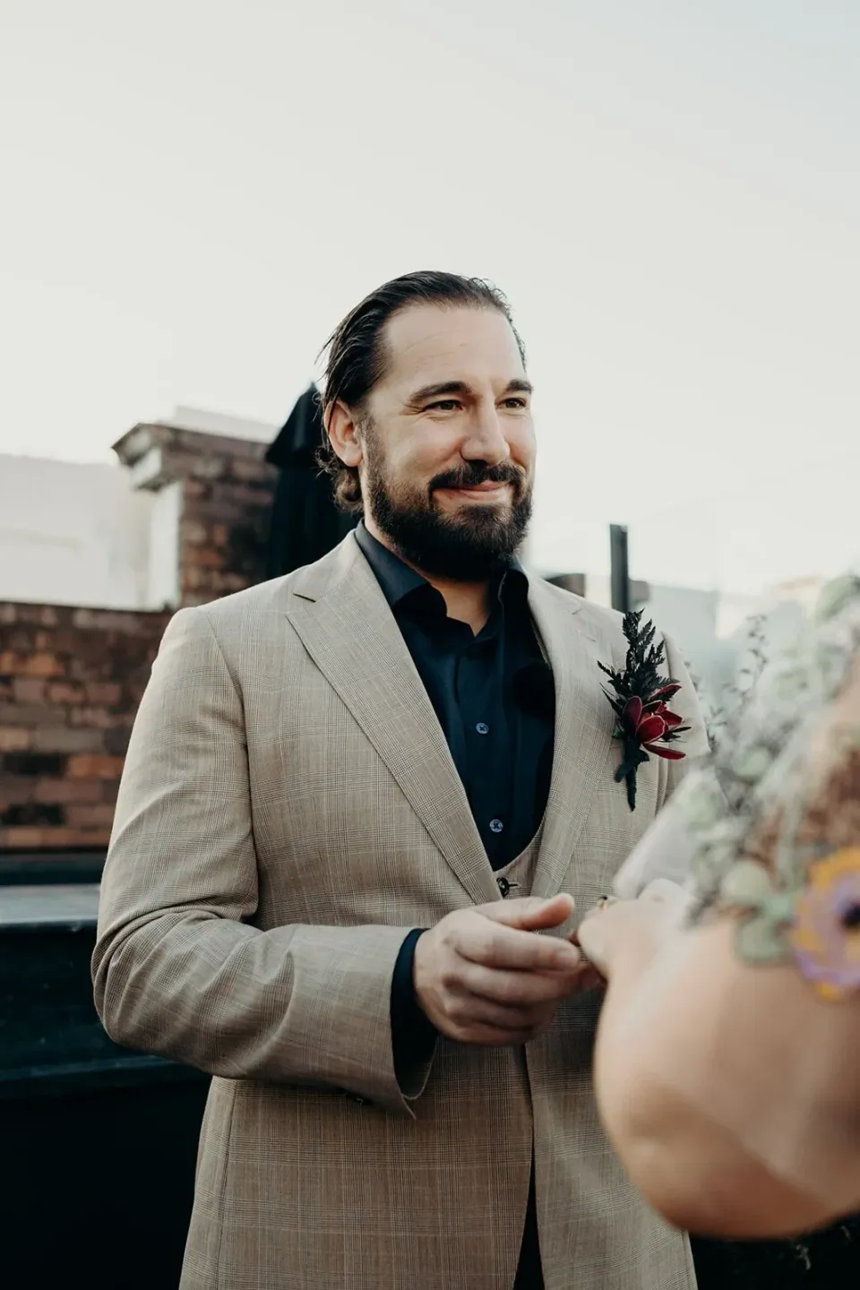 Daniel smiling at Victoria during their rooftop ring exchange, at Agnes Restaurant in Fortitude Valley, Brisbane, for an Elopement Collective elopement. Photo by Tessa Shannon.