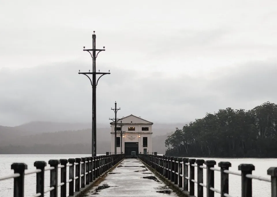 A long pier leads across a misty lake to the white Pumphouse Point building.