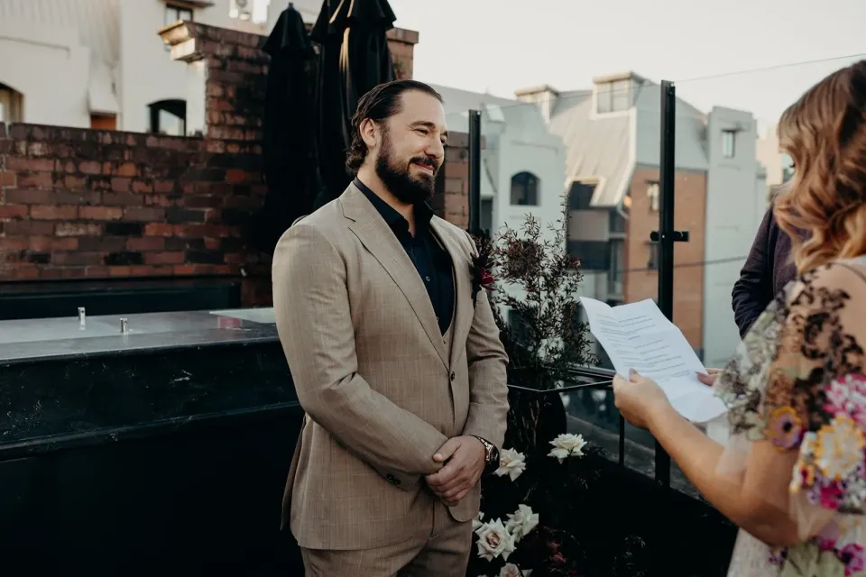 Daniel smiling at Victoria as she reads her vows, at Agnes Restaurant in Fortitude Valley, Brisbane, for an Elopement Collective elopement. Photo by Tessa Shannon.
