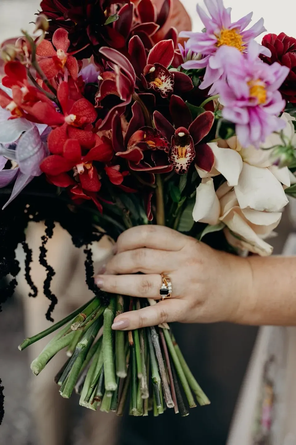 Close-up of Victoria’s wedding ring and hands around her bouquet of burgundy and purple flowers by Mrs Gibbons Flowers, at Agnes Restaurant in Fortitude Valley, Brisbane, for an Elopement Collective elopement. Photo by Tessa Shannon.