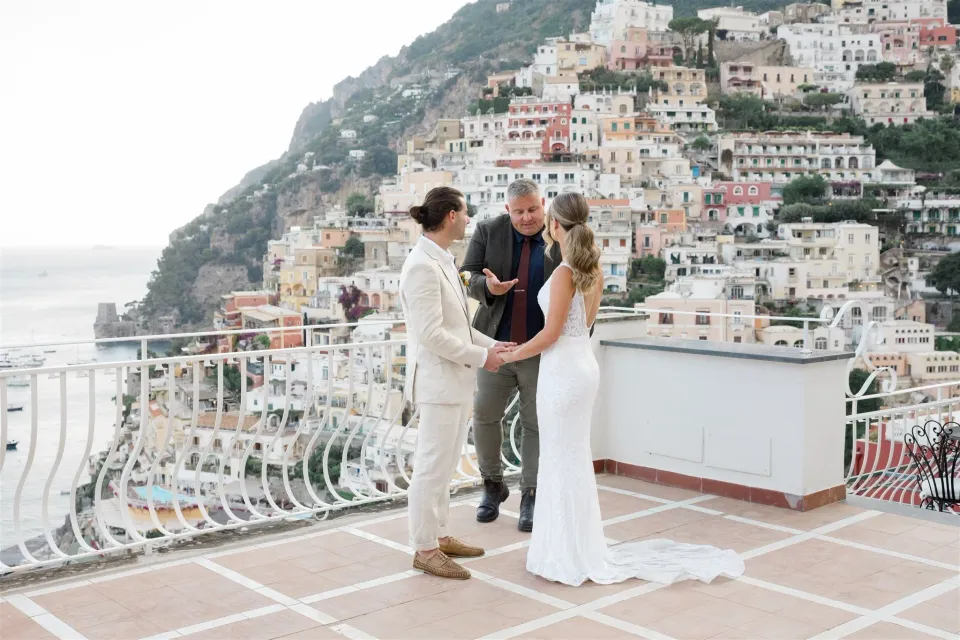 Sarah and Josh holding hands during their terrace ceremony with celebrant Josh Withers, at Alcione Residence in Positano, Amalfi Coast, Italy, for an Elopement Collective elopement. Photo by James from House of Love.