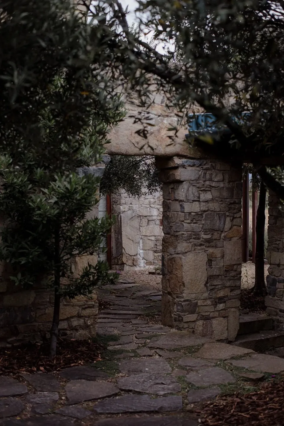 A shaded stone doorway opens onto a garden path.