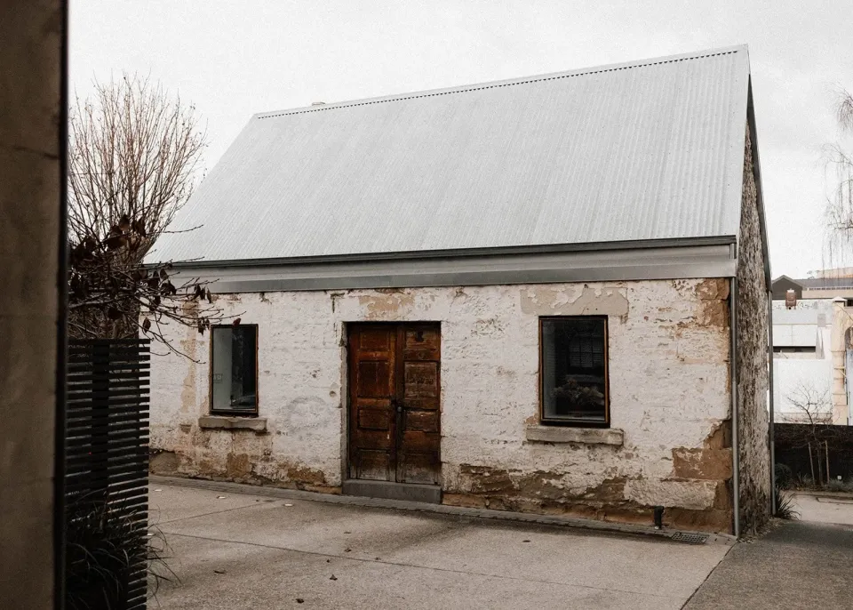 A weathered stone cottage with a steep metal roof and a timber front door.