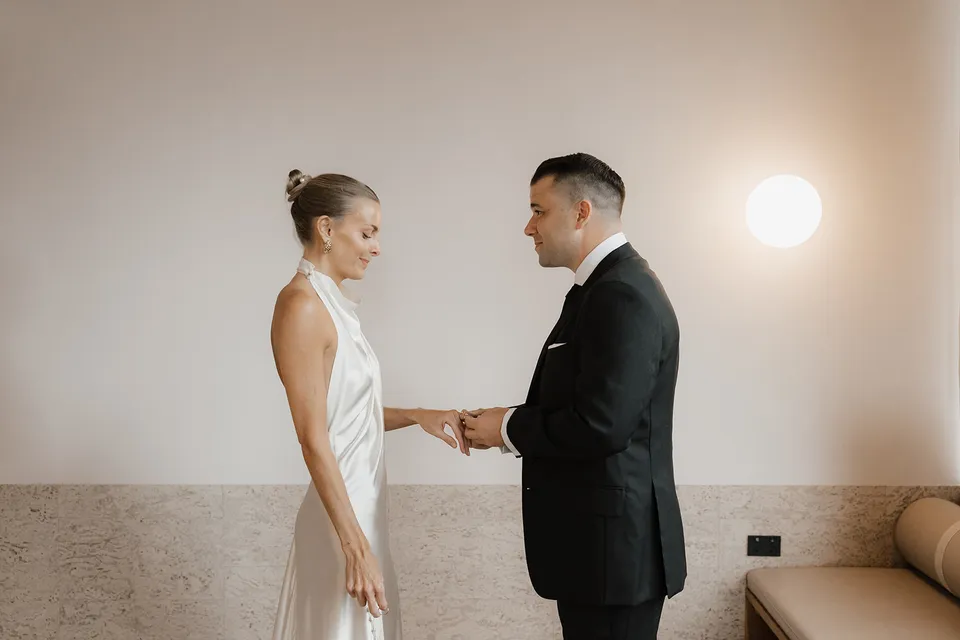Clare and Matt holding hands during their indoor ceremony, at The Calile Hotel in Fortitude Valley, Brisbane, for an Elopement Collective elopement. Photo by Harley from Bulb Creative.