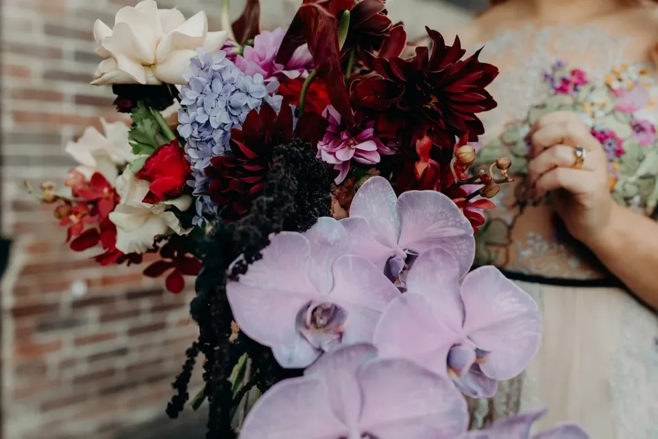 Detail of purple orchids, burgundy dahlias and pale blooms in Victoria’s bouquet by Mrs Gibbons Flowers, in Fortitude Valley, Brisbane, for an Elopement Collective elopement. Photo by Tessa Shannon.