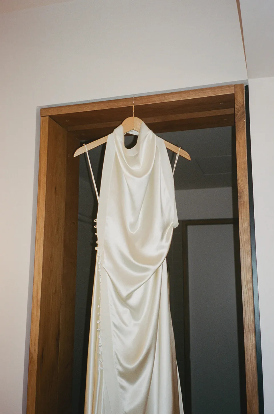 Clare’s draped ivory Sasha dress by Danielle Frankel hanging in the hotel suite, at The Calile Hotel in Fortitude Valley, Brisbane, for an Elopement Collective elopement. Photo by Harley from Bulb Creative.