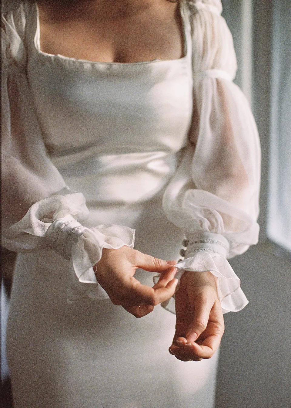 On 35mm film: Detail of Elyse's hands and gathered dress cuffs. At Fig Tree Villa in Ewingsdale, Byron Bay, for an Elopement Collective elopement. Photograph by Bulb Creative.